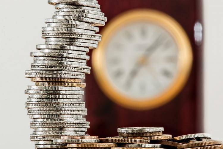 Silver and gold coins and a wall clock in the background.